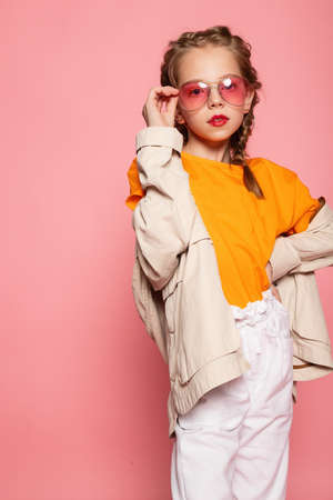 little girl in pink glasses. Trendy fashion style stylish funtime concept. Vertical full-size full-length portrait of laughing cute sweet adorable lovely charming girl isolated pink backgroundの写真素材