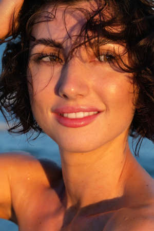 young brunette girl in a red swimsuit stands in the water during a hot summer. Beach photo from the sea.の写真素材