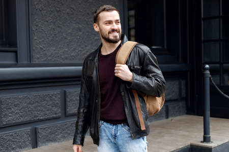 Full length portrait of male tourist with backpack from designer crossing across road and looking at cameraの写真素材