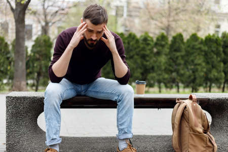 trendy guy with, walking in the city a cup of coffee in hand. depressed guyの写真素材