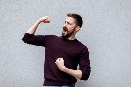 Photo of mature excited man happy smile celebrate win victory show cellphone fists hand isolated over gray color backgroundの写真素材