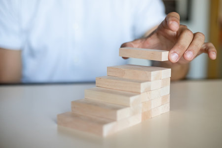 Hand arranging wood block stacking as step stair. Ladder career path concept for business growth success process, Copy spaceの写真素材