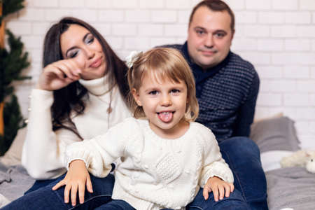 Merry Christmas and happy holidays Parents and young baby daughter girl have fun and play together near the Christmas tree indoors.の写真素材