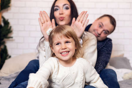 Merry Christmas and happy holidays Parents and young baby daughter girl have fun and play together near the Christmas tree indoors.の写真素材