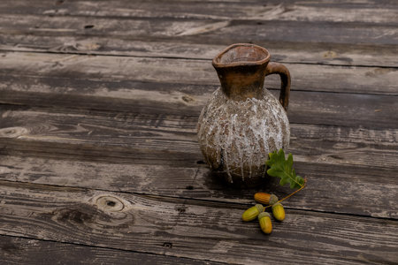 Still-life with jug and dry leaves of an oak on table. Composition of acorns from oakの写真素材