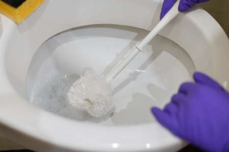 housekeeper cleaning a dirty toilet by using cleaning brush.の写真素材