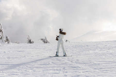 winter, leisure, sport and people concept - Girl snowboarder stands with snowboard on mountain's top on sunrise backdrop. Sheregesh ski resortの写真素材