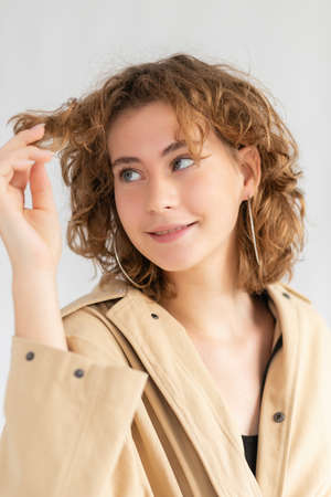 Portrait of Caucasian woman with smoothly tucked hair and natural makeup in raincoat with. woman looking at curly hairの写真素材
