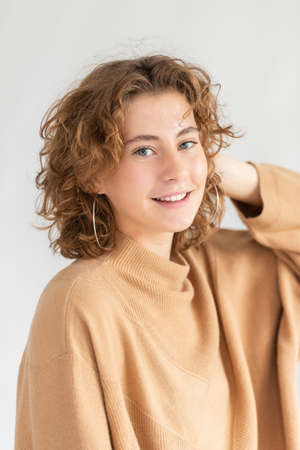 Woman with curly beautiful hair on gray background. Girl with beauty a pleasant smile. short wavy hairstyleの写真素材