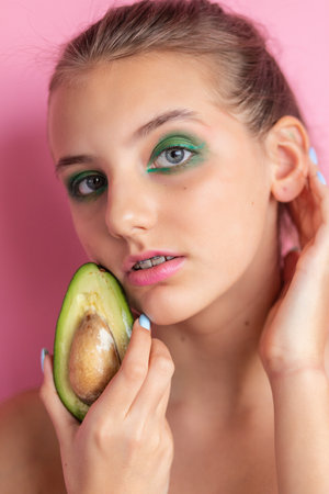 Close up view of gorgeous ginger woman with avocado. Studio shot of excited caucasian girl with healthy food isolated on pink background.の写真素材