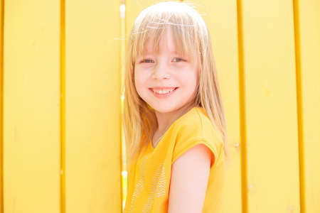 Pensive little ginger kid girl 12-13 years old in white t-shirt isolated on yellow background children portrait. Childhood lifestyle concept. Mock up copy space. looking up with hands behind headの写真素材