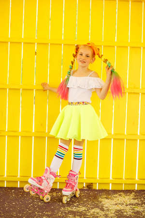 Little girl learning to roller skate in summer park. Children wearing protection pads for safe roller skating ride. Active outdoor sport for kids. Close up view of skatesの写真素材