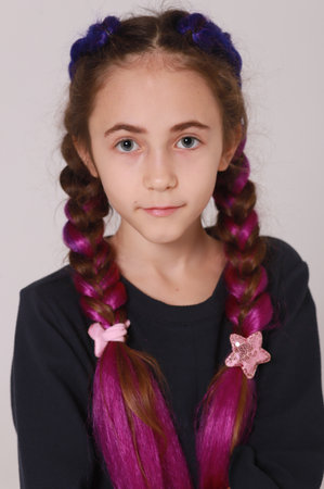 Cute girl in black dress and long braids on light gray backgroundの写真素材