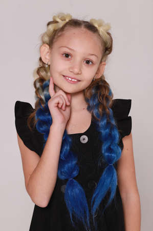 Cute girl in black dress and long braids on light gray background,smiling girlの写真素材