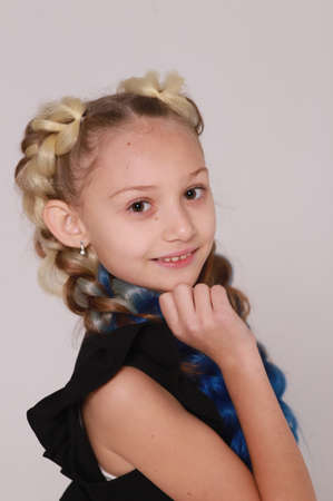 Cute girl in black dress and long braids on light gray background,smiling girlの写真素材