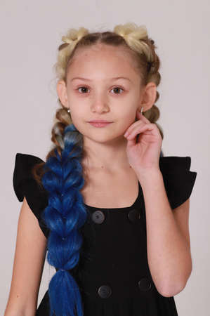 Cute girl in black dress and long braids on light gray backgroundの写真素材