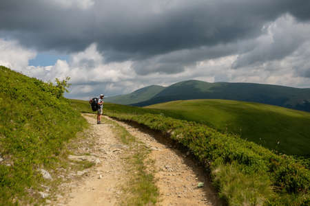 Solo hiking in the picturesque autumn mountain valley. Heavy climb in the mountains with a big backpack.Travel lifestyle, hiking hard track, adventure concept in autumn vacation.の写真素材
