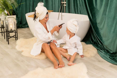 Happy family mother and child daughter in towel and bathrobe in the bathroom.の写真素材