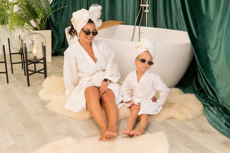 home spa. Mother and daughter make a clay facial mask. Beautiful young women with child doing beauty treatment together.の写真素材