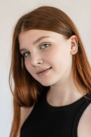 Portrait of an emotional red-haired girl with freckles and braces on a white background.の写真素材