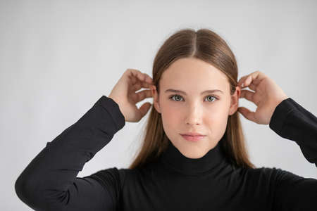 Amazing woman portrait. Beautiful girl wearing black golf, posing in studio over gray backgroundの写真素材