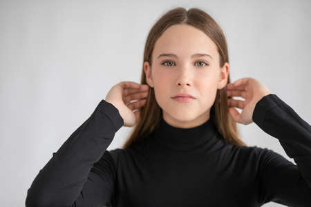 Amazing woman portrait. Beautiful girl wearing black golf, posing in studio over gray backgroundの写真素材