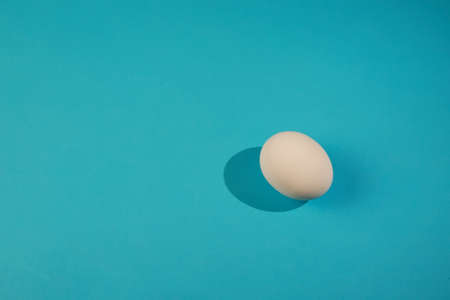 White egg on the blue background in center. Design, visual art, minimalismの写真素材