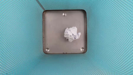 Trash can filled with crumbled paper isolated on blue backgroundの写真素材