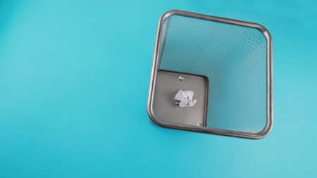Trash can filled with crumbled paper isolated on blue backgroundの写真素材