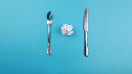 Crossed steel knife and fork on tredny soft blue paper background with side copy space,Crumble paperの写真素材