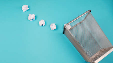 White crumpled paper beacons are thrown into the trash can. For copy space for designers on a blue backgroundの写真素材