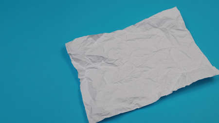 White crumpled sheet of paper lies on a table on a white background. On the sheet, a drawn lineの写真素材