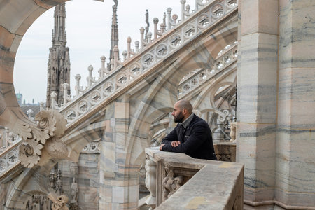Travel, holidays and winter vacations concept - Milan adventure: A carefree young man embraces Milan's beauty from above, his smile reflecting the joy of exploration on the roof of Milan Cathedralの写真素材