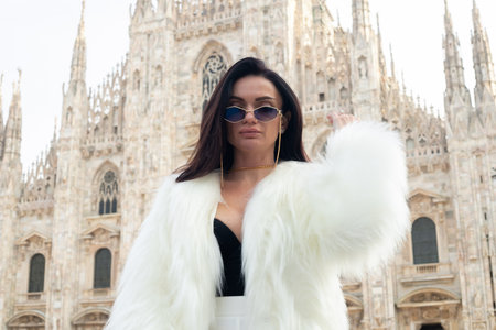 Joy of discovery: A young tourist girl feels free and alive in Milan, smiling against the backdrop of the majestic Milan Cathedral, embracing city life.の写真素材