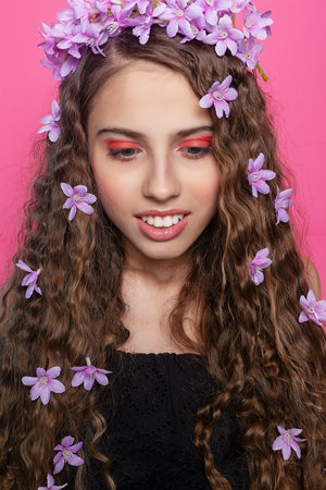 A vision of beauty with curly locks adorned by vibrant purple flowers, evoking a sense of natural allure and botanical charm.の写真素材
