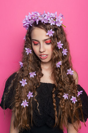 Beautiful girl with flowers in hair, glamorous hairdo. isolated. Fashion model with stylish makeup. girl looks away, purple flowers in her hair. fashion makeupの写真素材