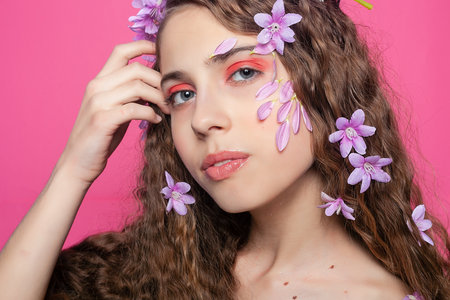 Romantic radiance: With curly hair adorned by purple flowers, the girl exudes a sense of romance and elegance in a whimsical botanical displayの写真素材