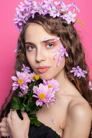 Floral fantasy: Curly-haired beauty embellished with purple flowers in her hair radiates grace and femininity in a dreamy botanical sceneの写真素材