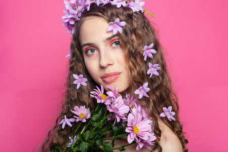 Floral fantasy: Curly-haired beauty embellished with purple flowers in her hair radiates grace and femininity in a dreamy botanical sceneの写真素材
