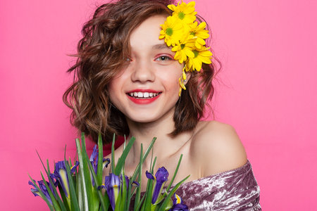 Tranquil portrait of a young woman, her face obscured by a bright yellow blossom against a pastel pink backdrop. Great for conveying serenity and tranquilityの写真素材