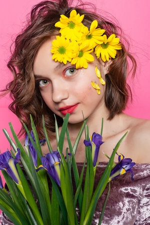 Ethereal photograph of a woman holding a yellow flower, her face partly hidden against a backdrop of pale pink. Suitable for expressing introspection and contemplation.の写真素材