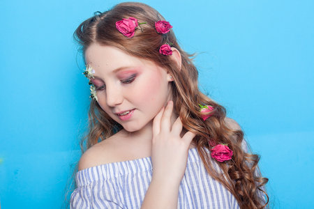 Adorable image of a girl with daisies adorning her face, creating a charming scene against the tranquil blue backdrop. Great for nature-inspired concepts.の写真素材