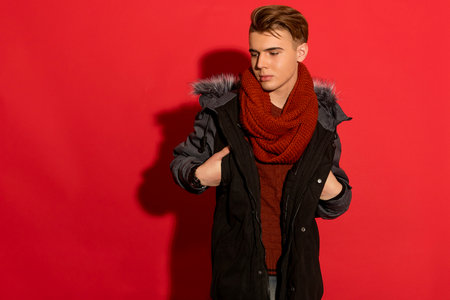Red-hot look! Stylish man in a jacket stands out against a vibrant red backdrop, adding flair and attitude to any project.の写真素材