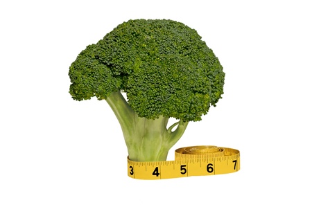 A fresh broccoli stalk with a yellow measuring tape wrapped around its base の写真素材