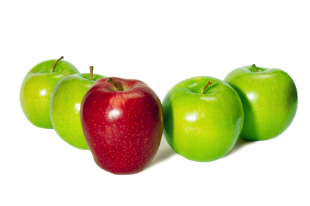 Horizontal shot of a red delicious apple standing in front of four green granny smith apples on a white background.の写真素材