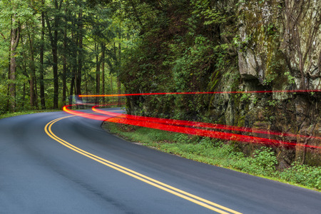 Horizontal shot of Automobile Tail Lights Streaking Around a Smoky Mountain Curve.