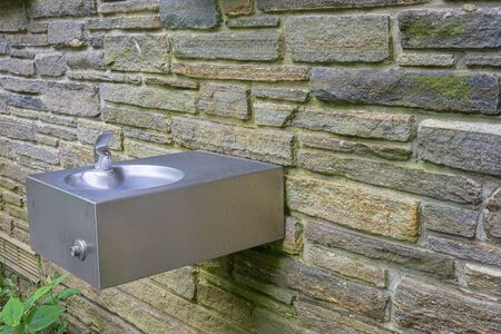 Horizontal shot of an outdoor drinking fountain in the Great Smoky Mountains National Park mounted to a stone wall.の写真素材