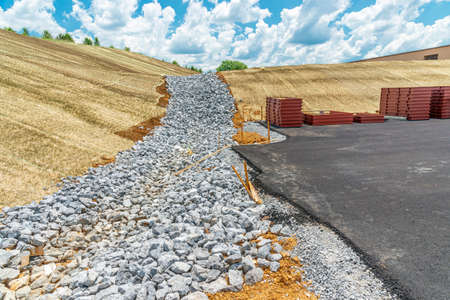 Horizontal shot of a drainage ditch preparation at a new construction building site.  Blue sky with...