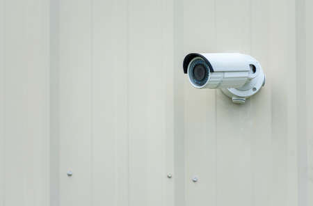 Horizontal shot of an outdoor security camera on a plain wall with copy space.の写真素材