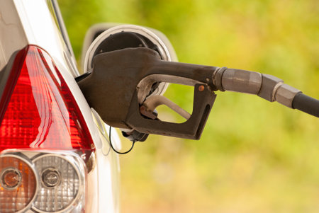 Horizontal shot of a gasoline nozzle in the gas tank opening of a car.の写真素材
